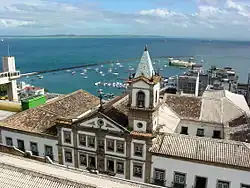 Vista aérea sobre as edificações históricas do Centro e ao fundo à esquerda, o Elevador Lacerda e a Baía de Todos-os-Santos com o Forte de São Marcelo ao centro.