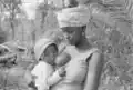 Mãe de pé a amamentar o seu bebé, Canjambari, Guiné-Bissau, 1973