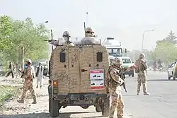 Armed soldiers in and around a military vehicle