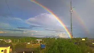 Um arco-íris sobre a cidade, com a Serra da Bela Adormecida ao fundo.