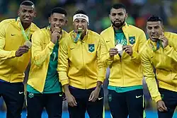 Cinco homens lado a lado, cada um segurando uma medalha de ouro com as mãos.