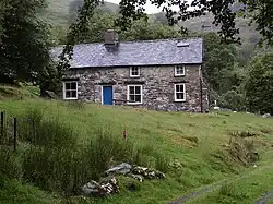 Uma fotografia a cores de uma casa de pedra em uma colina.