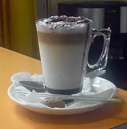 A caffè mocha sitting on a white plate and beige table.
