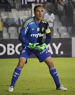 Um goleiro de pé, atento à alguma jogada fora da câmera