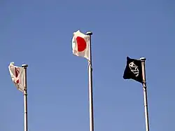 Três bandeiras tremulam no céu.