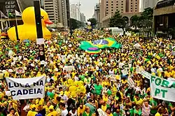 Manifestantes de verde e amarelo se manifestando em defesa da Operação Lava Jato, segurando cartazes que dizem "Lula na cadeia!" e "Fora PT!"