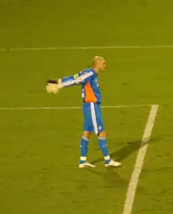 Um goleiro com os braços para trás do seu corpo, se alongando