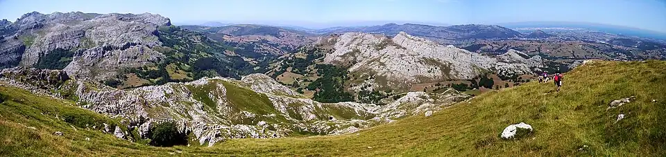 Panorâmica desde o Alto de Brenas (579&nbsp;m de altitude), em Riotuerto, da cordilheira Cantábrica (à esquerda) e da Marina&nbsp;[es], com a cidade de Santander ao fundo e à direita