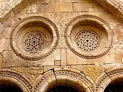 Frisos em forma de dente de cão circundam o arco e as rosáceas, com traceria de inspiração islâmica. Claustro