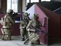 Três membros da equipe de airsoft defendendo uma área durante um jogo CQB interno.
