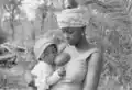 Mãe de pé a amamentar o seu bebé, Canjambari, Guiné-Bissau, 1973