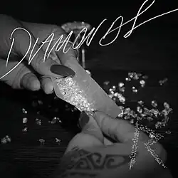 Imagem em preto e branco na qual são mostradas duas mãos ao centro segurando um papel de enrolar cigarro recheado com vários diamantes, com outros espalhados em cima de uma mesa onde os braços estão apoiados. O nome "Diamonds" está de forma estilizada e apresentada na parte superior da fotografia, e no canto inferior direito é apresentado o logotipo "R".